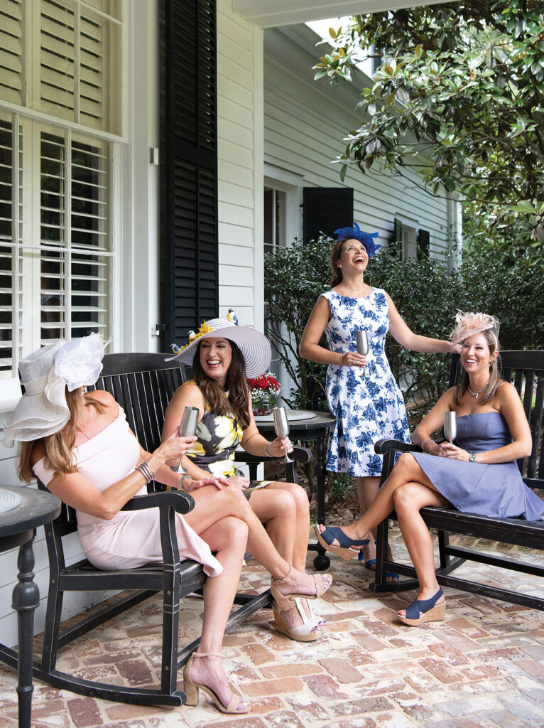 Girls sitting on a porch in Kentucky Derby style dresses and hats