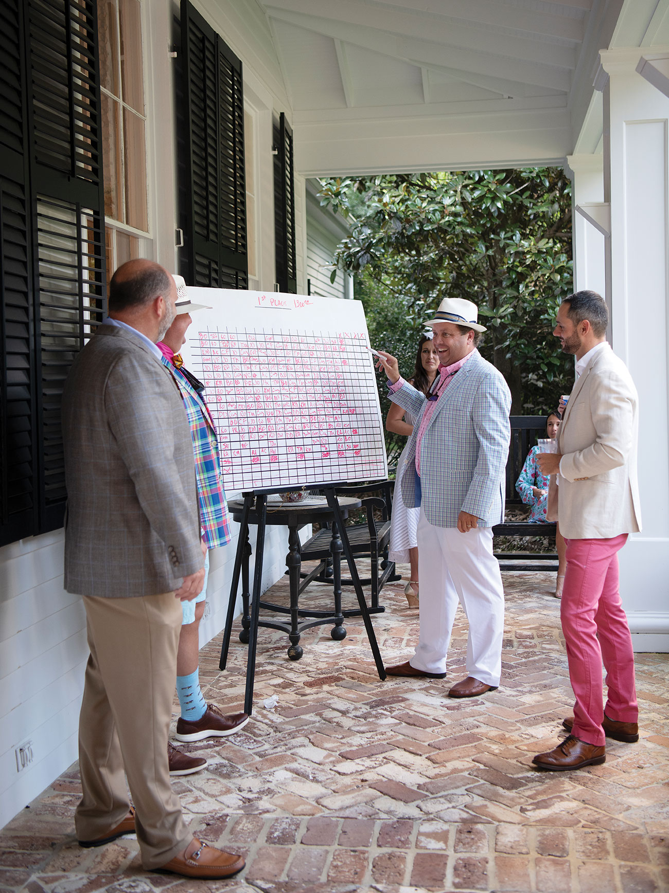 Men talking on a porch wearing Kentucky Derby style outfits