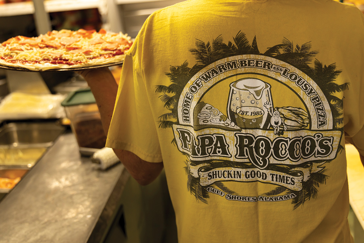 Waiter holding a pizza wearing a Papa Rocco's t-shirt