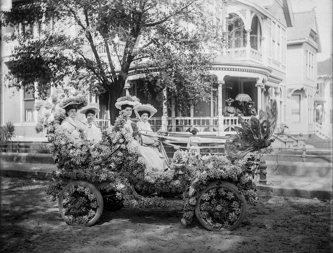 Women riding a carriage in the original floral parade