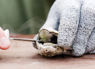 hand shucking a roasted oyster