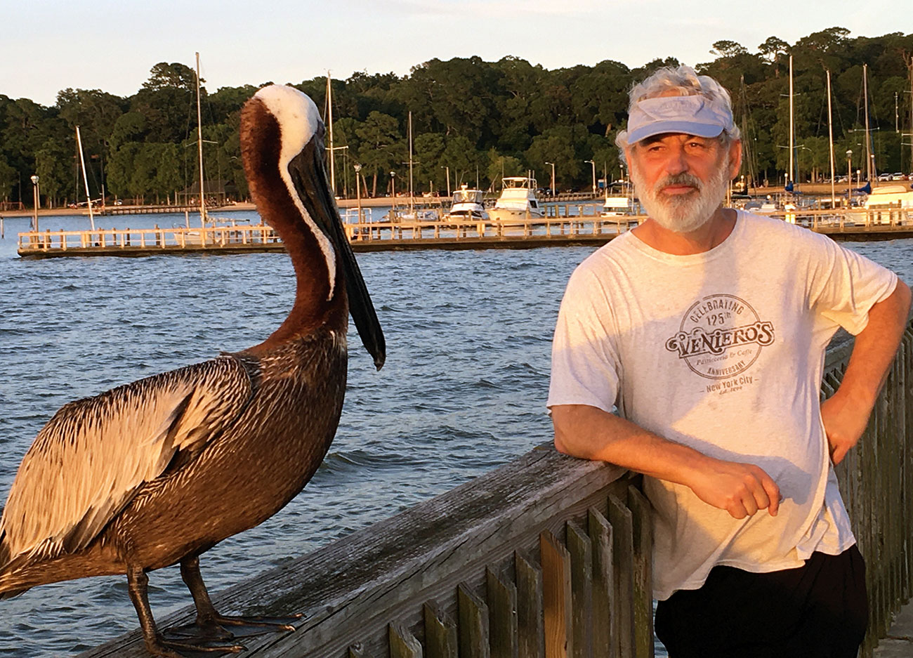 Roy Hoffman standing next to a pelican on the Fairhope Pier