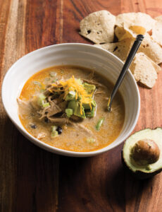 White Chicken Chili with tortilla chips and avocado on the side