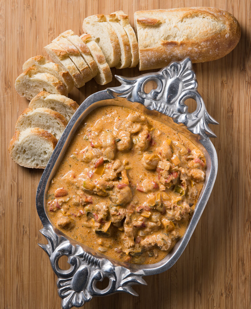 Crawfish dip served on a wooden board with french bread slices