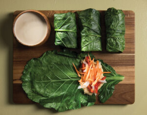 Healthy Collard Green Wraps on a cutting board served with Tahini sauce