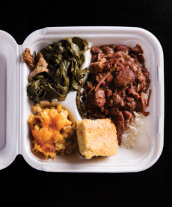 styrofoam box with Southern staple foods like cornbread, mac and cheese, red beans and rice and collard greens.