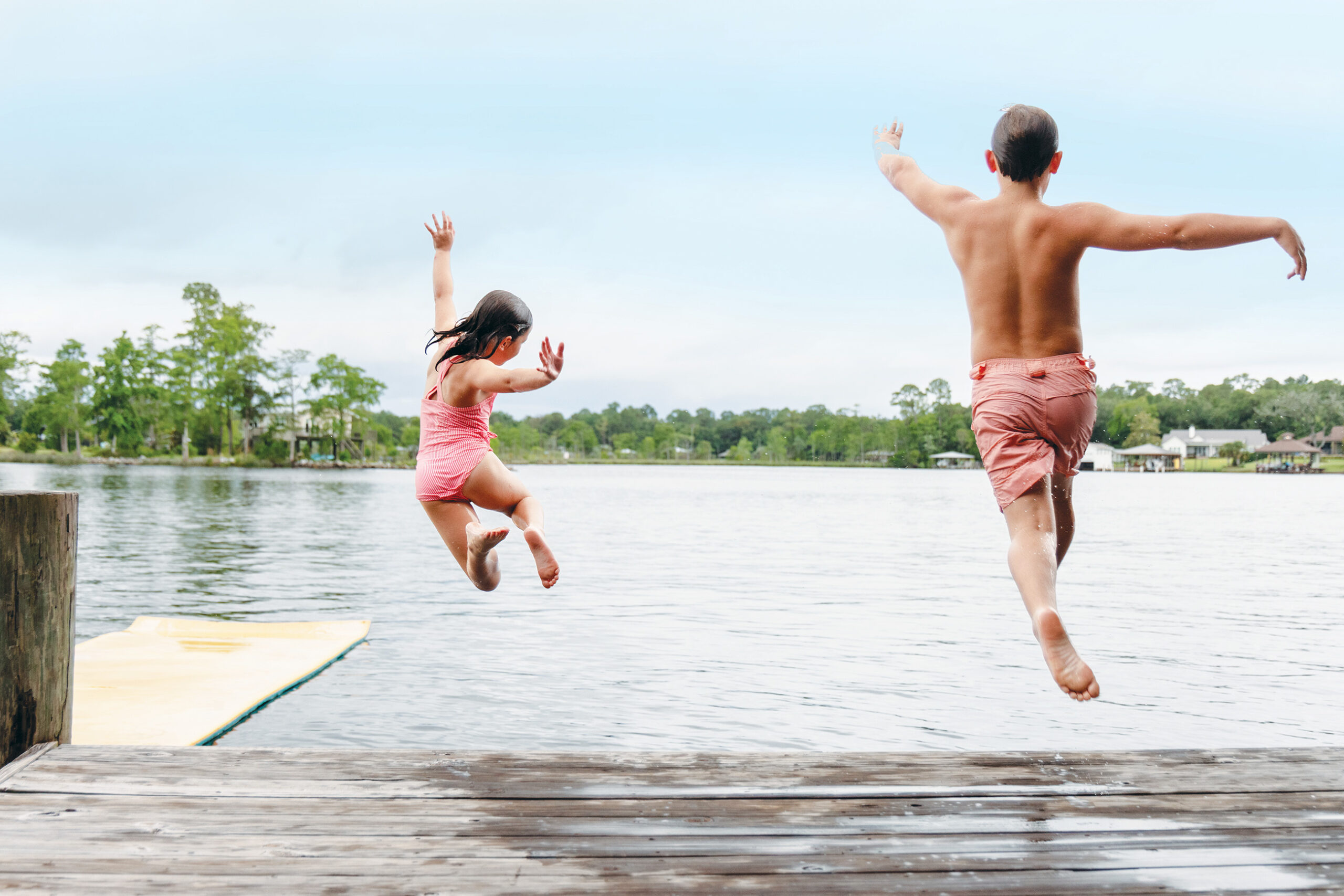 Two kids jumping off a wharf into Fowl River
