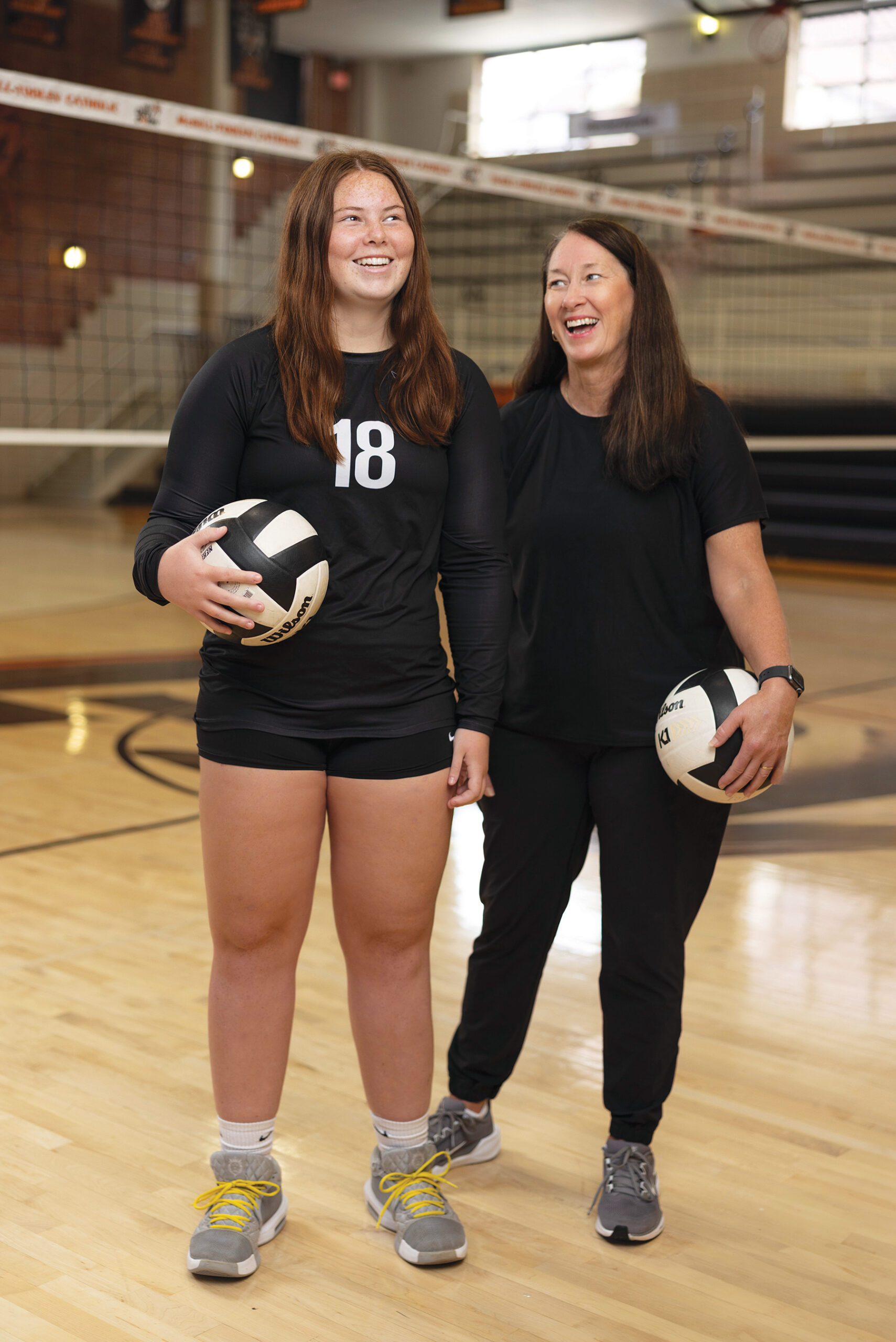 Mother and daughter holding balls on a volleyball court