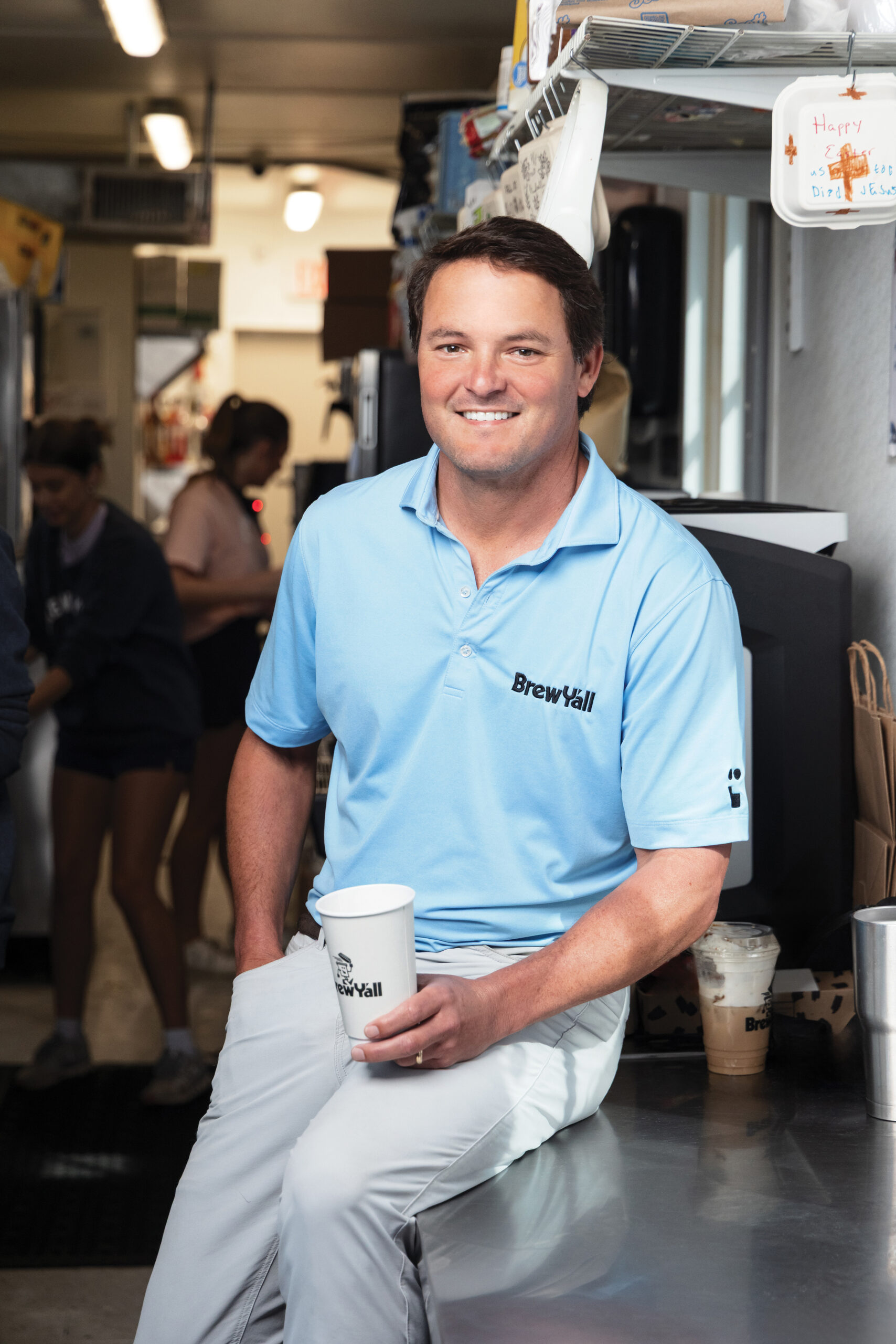 Richard Sanders sitting on the counter of his coffee shop